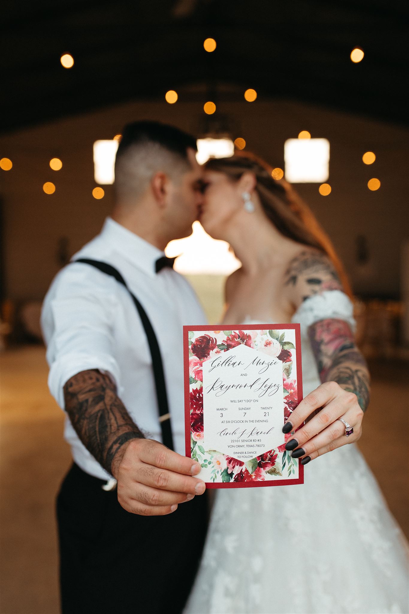 A bride and groom sharing a kiss while holding their San Antonio wedding invitation.